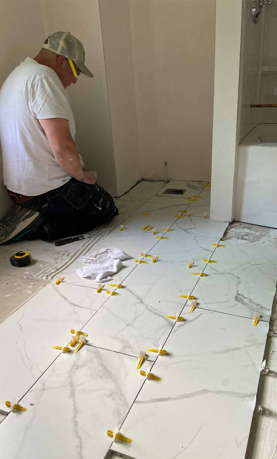 bathroom-remodel_tile-flooring Joshua Caron from Caron Home Remodeling installing a bathroom tile floor.